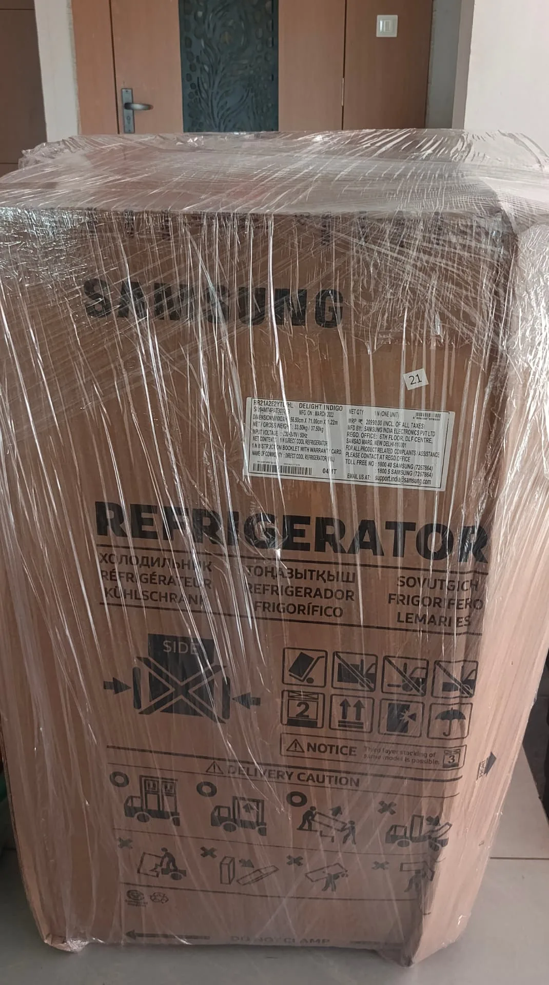 Insured packers and movers Surat wrapping a refrigerator in protective film before transit